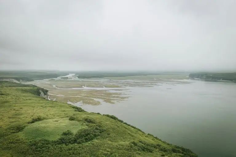 Misty landscape with winding river through green rolling hills